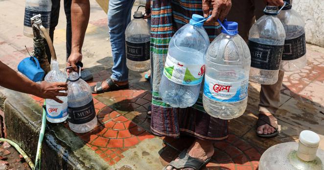 Des passants et des ouvriers collectent de l'eau, à Dhaka, au Bangladesh, le 26 avril 2025.