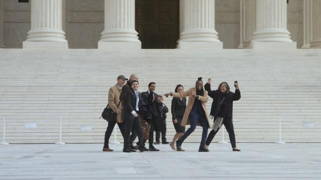 ACLU attorney Chase Strangio (at left, in suit and tie) joins a group on the steps the U.S. Supreme Court in Washington, DC.