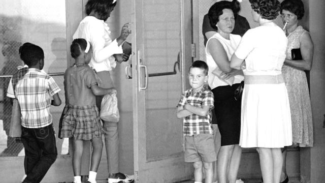 A group of African American students, left, enter the Boothville-Venice School in Plaquemines Parish, Louisiana on Sept. 12, 1966 as a group of white mothers wait at the entrance of the school. (AP Photo/Jack Thornell, file)