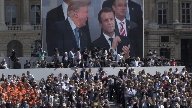 President Donald Trump, pictured on screen from left, French President Emmanuel Macron and White House Chief of Staff Reince Priebus watch a Bastille Day parade on the Champs Elysees avenue in Paris, July 14, 2017. (AP Photo/Carolyn Kaster, File)