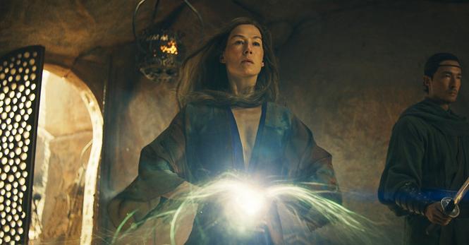 A woman in a flowing blue robe holding her hands together to summon a ball of light.
