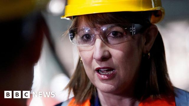 Rachel Reeves wears a yellow hard hat, safety googles and a high visibility vest as she listens to someone during a visit to the British Steel plant in Scunthorpe.