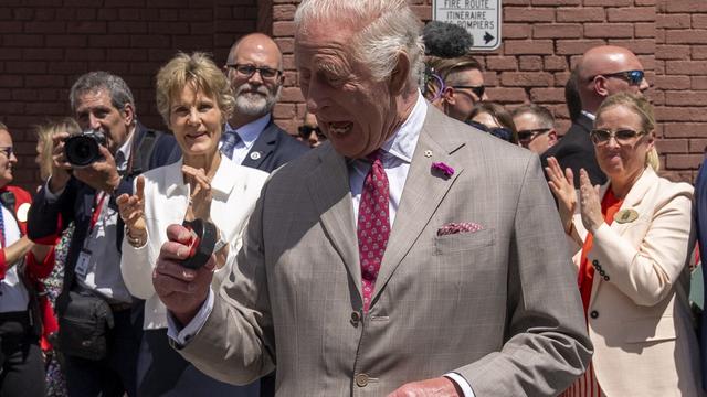 King Charles looks at the puck after participating in a ceremonial puck drop during a visit to Lansdowne Park in Ottawa, Canada, on Monday, May 26, 2025. (Christinne Muschi/The Canadian Press via AP)