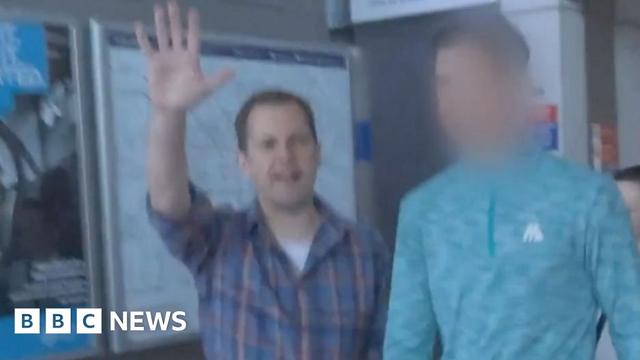 A screengrab of Robert Jenrick holding up his hand as he confronts a fare dodger, whose face is blobbed out, at a Tube station.