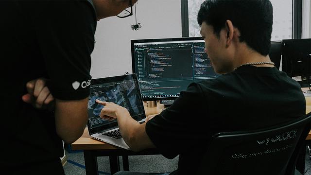 Two men looking at a computer screen with code on it.