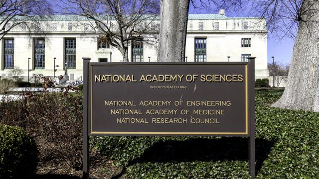 Image of a science in front of a marble building, declaring that the building hosts the National Academies of Science. Image of a science in front of a marble building, declaring that the building hosts the National Academies of Science.