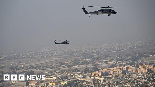 An aerial shot above the city with two helicopters in the air above it