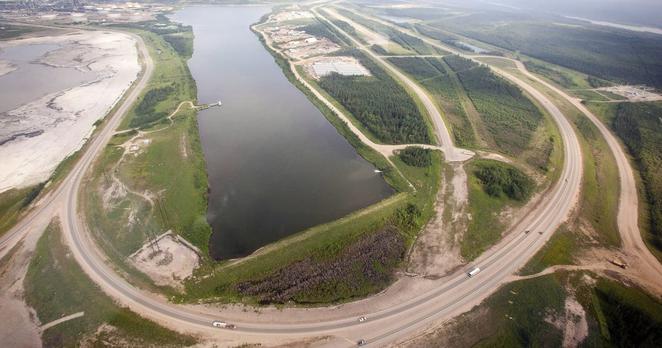 A highway loops around a tailings pond at the Syncrude facility as seen from a helicopter tour of the oil sands near Fort McMurray, Alta., on July 10, 2012. THE CANADIAN PRESS/Jeff McIntosh
