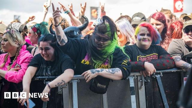 Rock fans at Download festival enjoying a performance. Four women are prominent at the front of the crowd as they rest on a crash barrier. They are mostly wearing black T-shirts and three have brightly coloured hair Rock fans at Download festival enjoying a performance. Four women are prominent at the front of the crowd as they rest on a crash barrier. They are mostly wearing black T-shirts and three have brightly coloured hair
