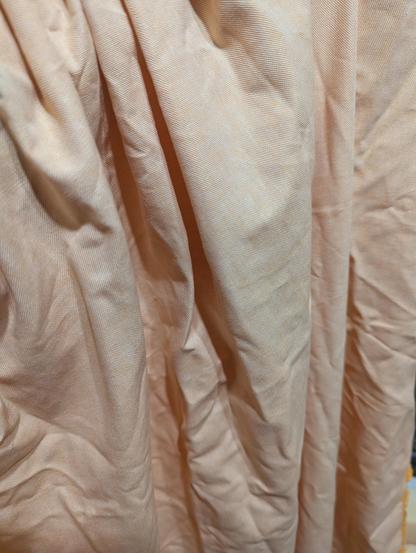 Fabric hanging roughly off of my left arm, photographed under "daylight" bulbs in the kitchen. It's a washed out orange, like Tupperware after you stored Bolognese sauce in it. 