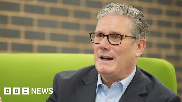 Sir Keir Starmer, wearing glasses and sitting on a green sofa.