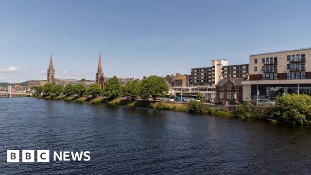 The River Ness flows through Inverness. There are two spires on the bank.