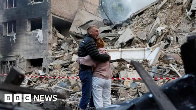 Residents react at the site of an apartment building damaged during a Russian strike on Kyiv.