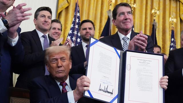 President Donald Trump holds up the signed document after signing the GENIUS Act, a bill that regulates stablecoins, a type of cryptocurrency, in the East Room of the White House, Friday, July 18, 2025, in Washington. (AP Photo/Evan Vucci)