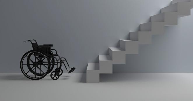 Ein leerer Rollstuhl steht vor einer weißen, nach oben führenden Treppe.
