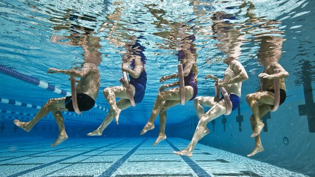 An underwater shot of five people sitting on swimming floats in a line at a pool in California (Credit: Getty Images)