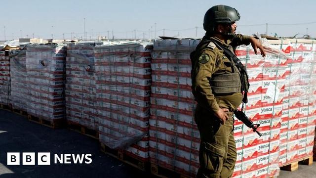 An Israeli soldier stands next to the parcels of humanitarian aid An Israeli soldier stands next to the parcels of humanitarian aid