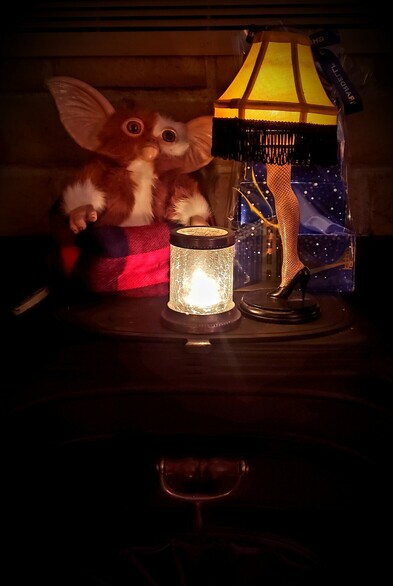 Wood stove mantel with Gizmo and the leg lamp from A Christmas Story lit by a candle. 