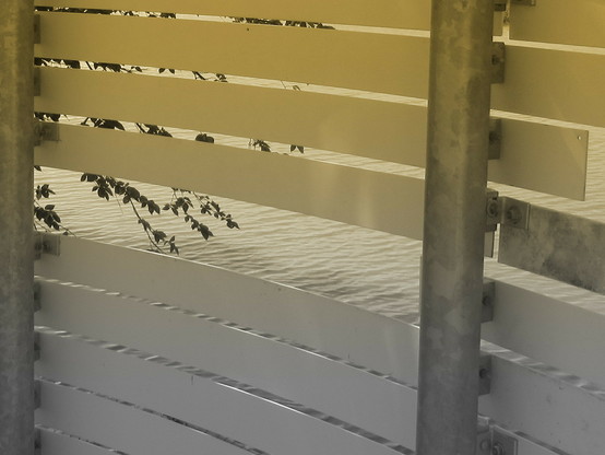 An unfinished bridge section that I found while hiking. White and metal slats set against a rippling creek that is barely visible. 