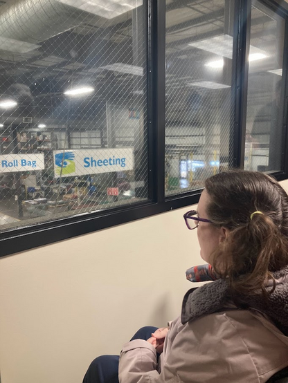 Julia looking through the glass at the factory below. She is sitting in her wheelchair. The only sight required job is to drive a forklift. So many different types of products are manufactured here. 