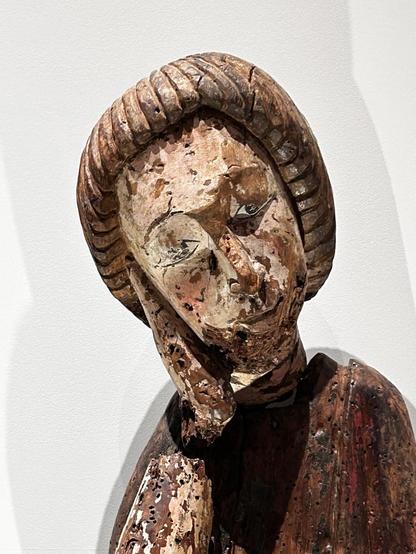 Closeup of head of St. John, which is tilted and resting on his hand. 