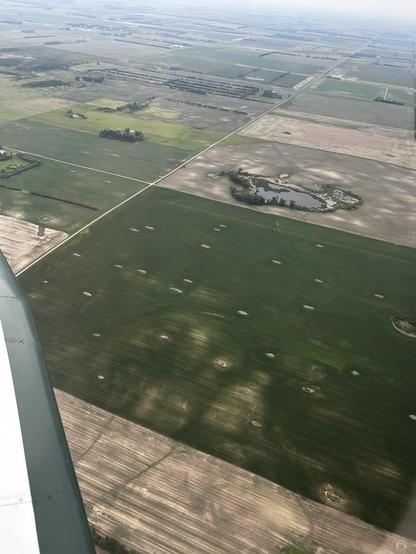 Oblique view from the air of a number of Farmfield's one of them has numerous rock piles scattered throughout.
