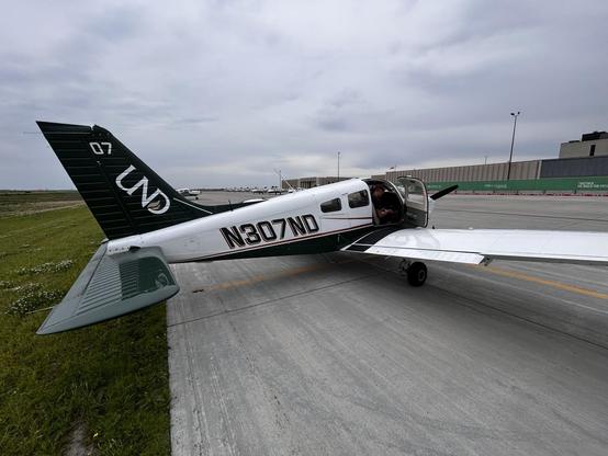 Ground photo of the Piper single engine plane with UND (University of North Dakota) markings