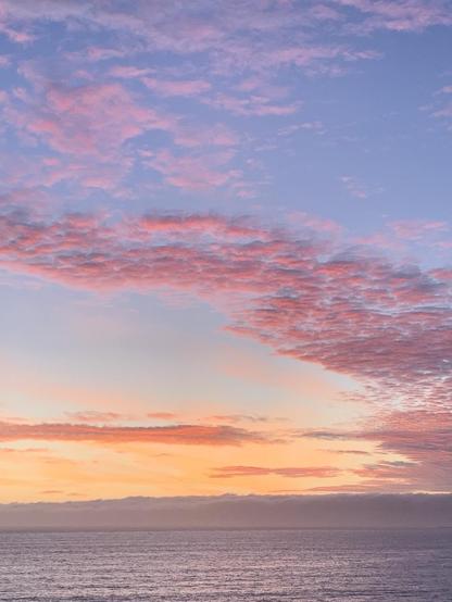 Ocean in the foreground, with multi hued clouds above