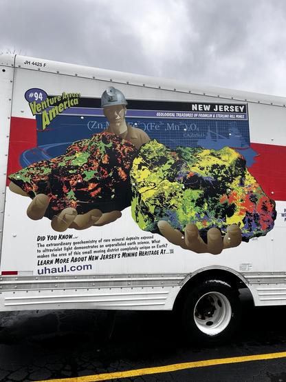 Image on the side of a truck of someone holding brightly colored fluorescent minerals toward the viewer 