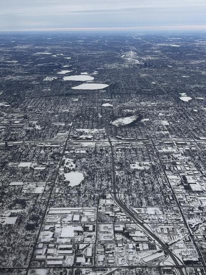A grid patterned urban area covered with snow, showing streets and highways, punctuated by frozen lakes
