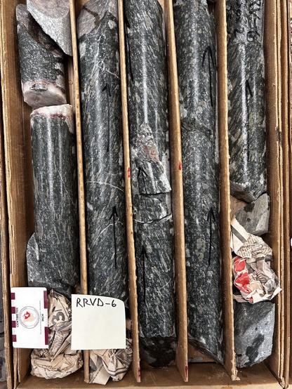 Box containing  dark colored schistose drill core