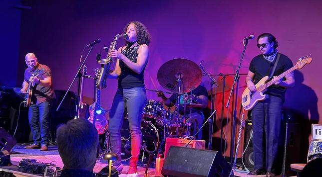 Vanessa on the saxophone with her bandmates on guitar, bass and drums 