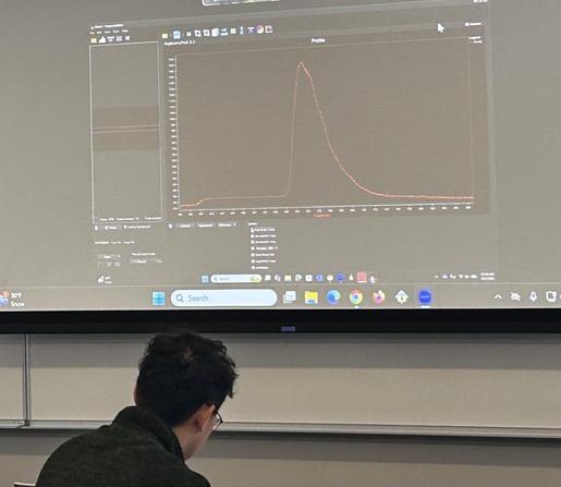 A light spectrum projected on a screen. shows a sharp peak with a shoulder on the right side.