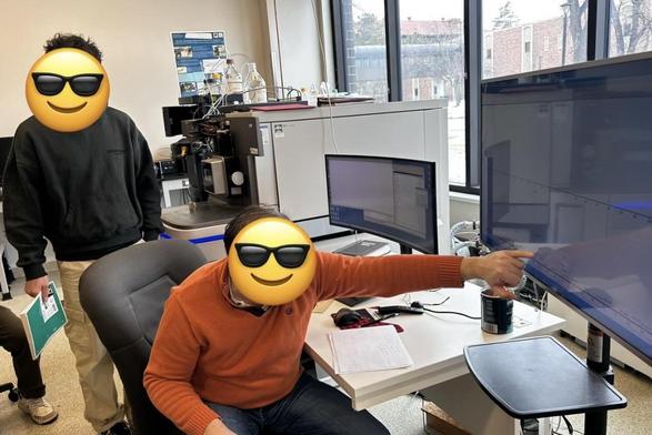 Two people in an instrument room. One is pointing at a screen.