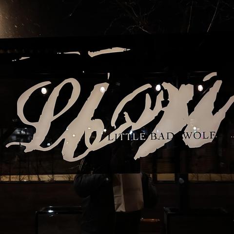 A dark window with a painted stylized logo and the name LITTLE BAD WOLF