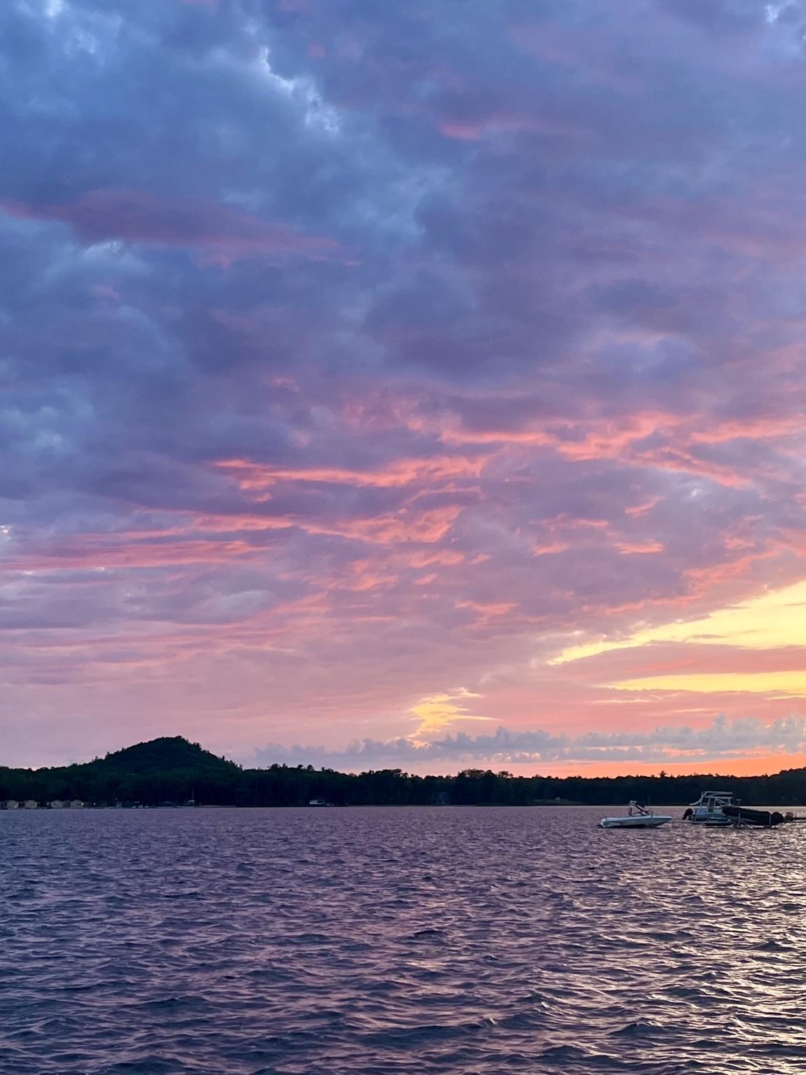 A sunset with blue clouds above and the bottoms are lit up with pink and orange.