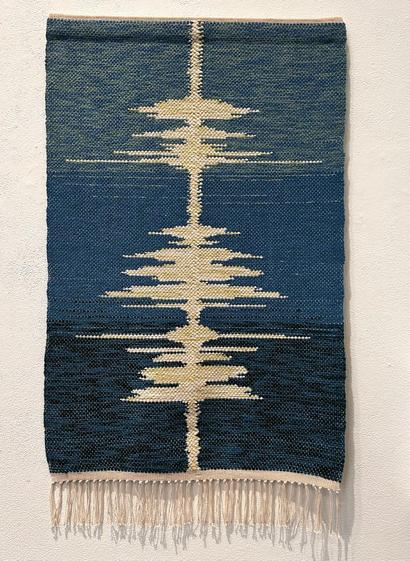 A fringed woven rug with background in shades of blue. A pattern along the long axis represents an audio spectrum.

Not shown: headphones in which one can hear the artist speaking the text.