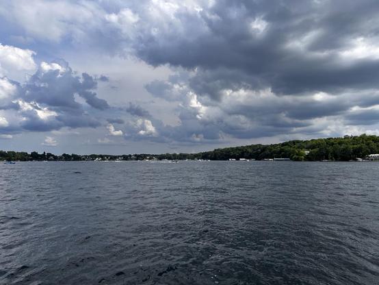 Lake scene with fluffy clouds and forested shoreline in the distance 