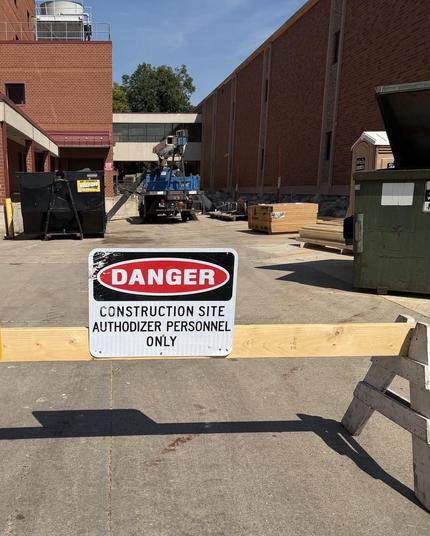 A barrier with a sign that says
DANGER
CONSTRUCTION SITE
AUTHODIZER PERSONNEL
ONLY
In the background, construction equipment.