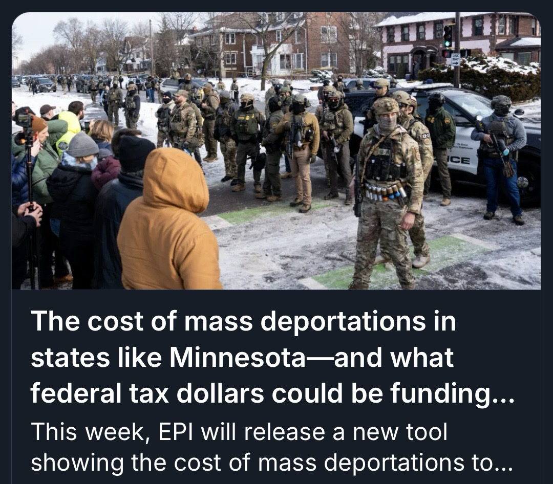 A large crowd gathers on a snowy street, facing a line of armed law enforcement officers. The background features residential buildings and police vehicles. The image relates to discussions about the costs of mass deportations in Minnesota.
